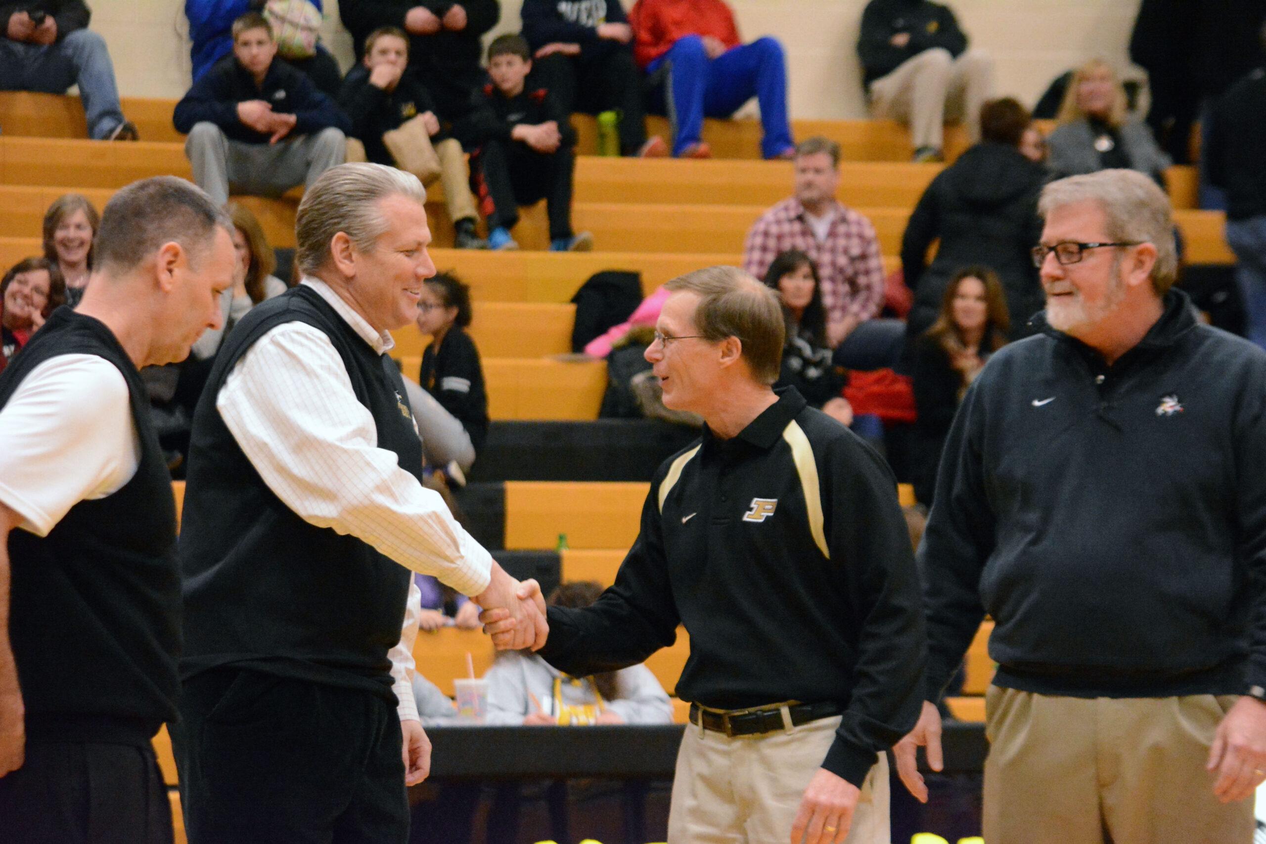 Retiring athletic director Ray Pohlman is congratulated by Superintendent Tom Hosler.