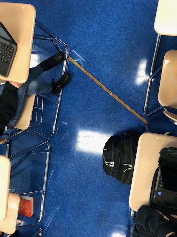a meter stick between desks to display the amount of social distancing in class rooms