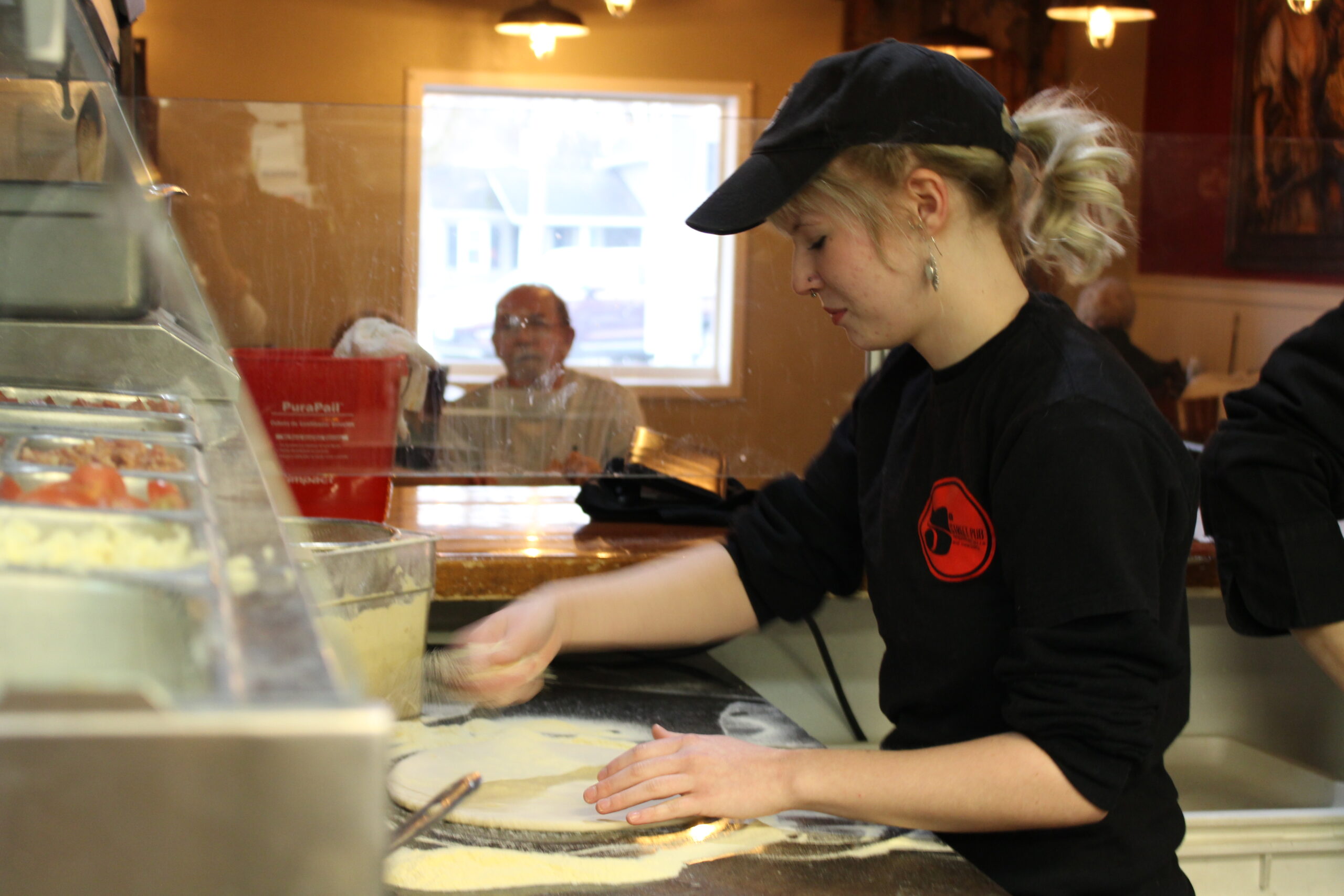 Sophie Rahe sprinkles cheese on pizza dough